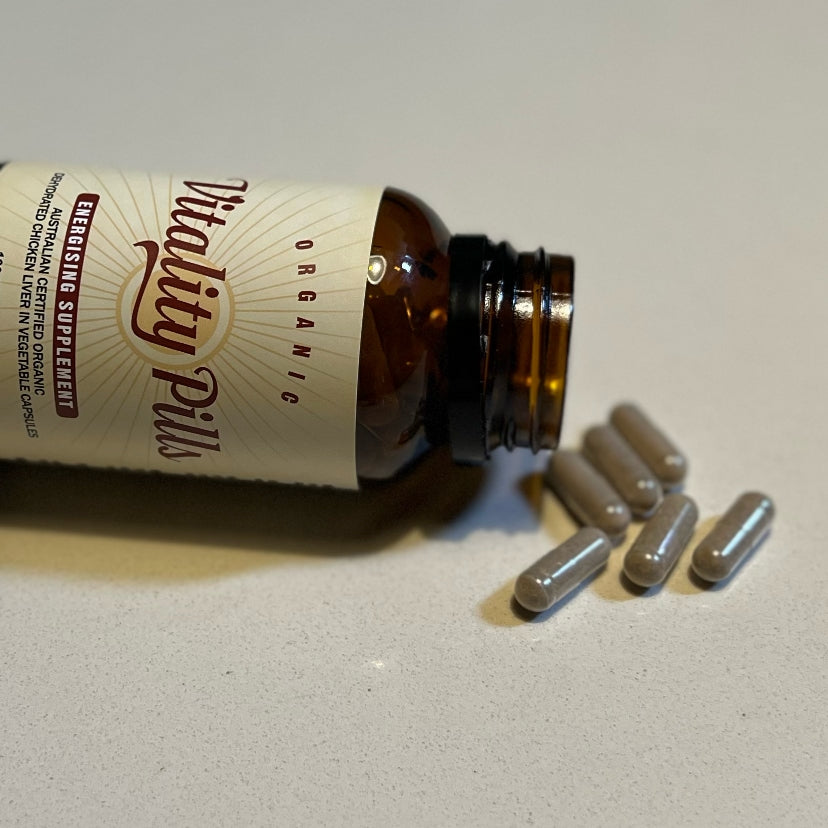 Amber glass jar tipped on side with organic chicken liver capsules pouring out - jar of Vitality Pills
